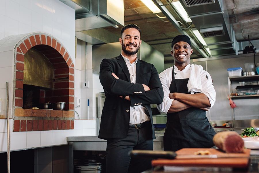 Business Insurance - Restaurant Manager with Chef in Kitchen Smiling by Brick Oven